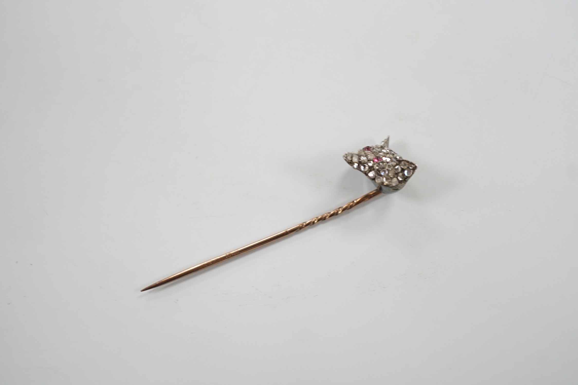 A late Victorian yellow and white metal, cabochon ruby? and rose cut diamond set fox head stick pin, 56mm, gross weight 4.7 grams (two stones missing).